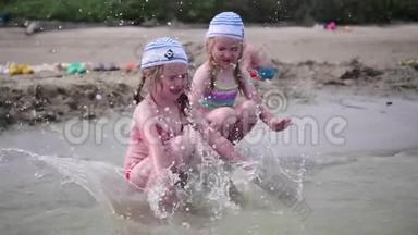 两个女孩在海滩上泼水。 在炎热的夏日里，双胞胎倒着水，<strong>孩子</strong>们的<strong>笑声</strong>和好心情